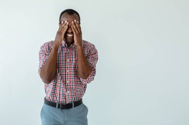 Buna inanamıyorum. Overjoyed gülümseyen afro Amerikan adam elleri ile yüzünü kapatarak ve beyaz arka plan karşı duran