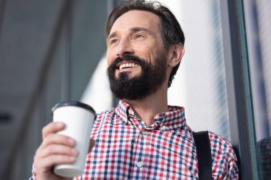 Sabah havası. Kenara bakarken kahve içen neşeli sakallı bir adamın yakın