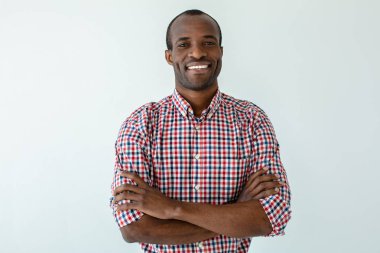 Kendine güvenen bir duruş. Beyaz arka plan karşı gülümseyen ve el katlayarak neşeli yakışıklı afro amerikan adam Bel kadar