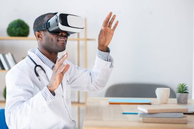 Hoş bir etkileşim. Kollarını havada tutarken yarı pozisyonda oturan yakışıklı sağlık çalışanı