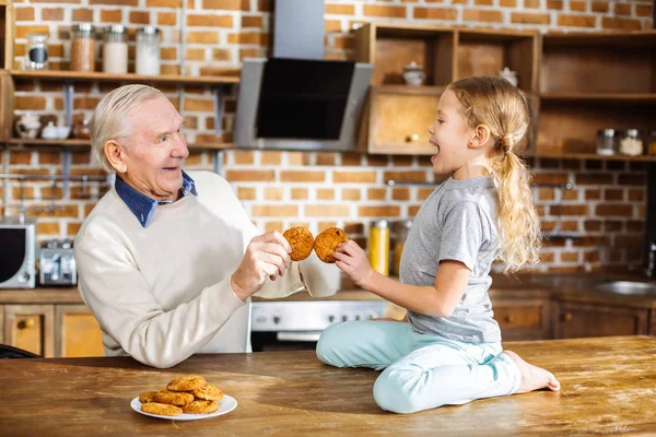 享受味道 欢快的老人吃回家做糕点与他的孙女 同时表达喜悦 — 图库照片