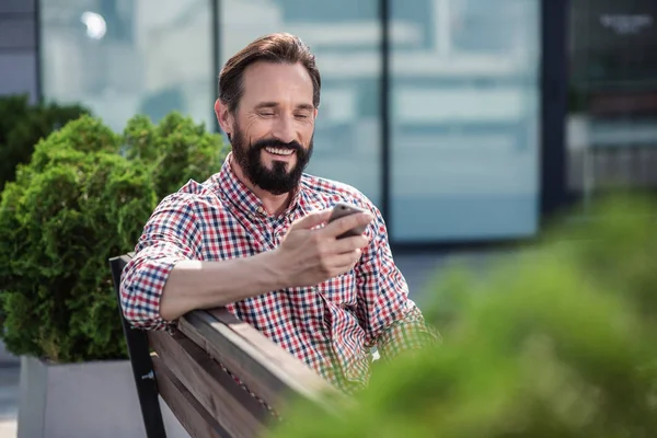 Vol Energie Vrolijke Knappe Man Zittend Bank Tijdens Het Typen — Stockfoto