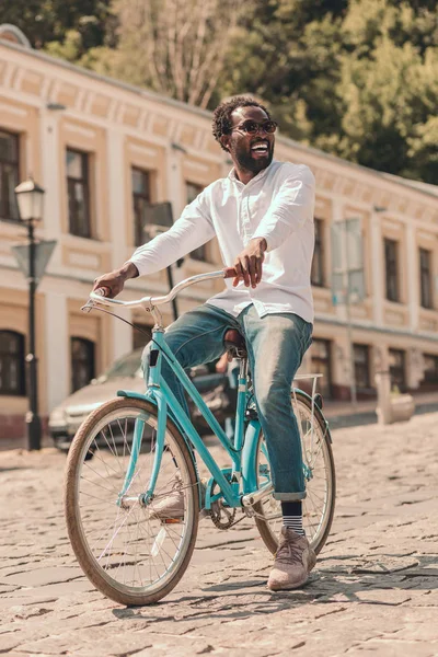 Happy young man cycling in the city on a stone street