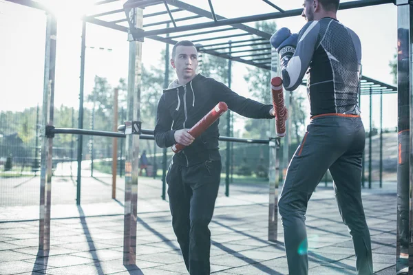 Kalm Geconcentreerde Trainer Staande Met Boks Stokken Het Sportveld Kijken — Stockfoto