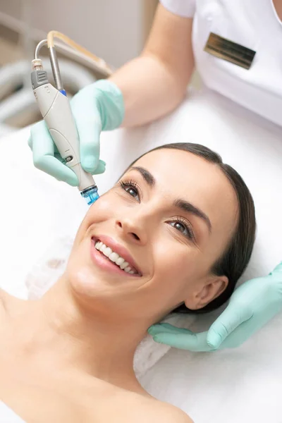 Profesyonel klinikte yüz derisinin dermabrazyonuna sahip pozitif koyu saçlı kadının yakın lığı