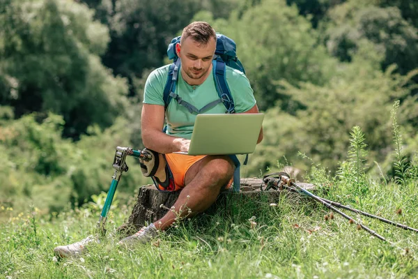 Jovem Turista Agradável Sentado Toco Árvore Enquanto Usa Seu Laptop — Fotografia de Stock