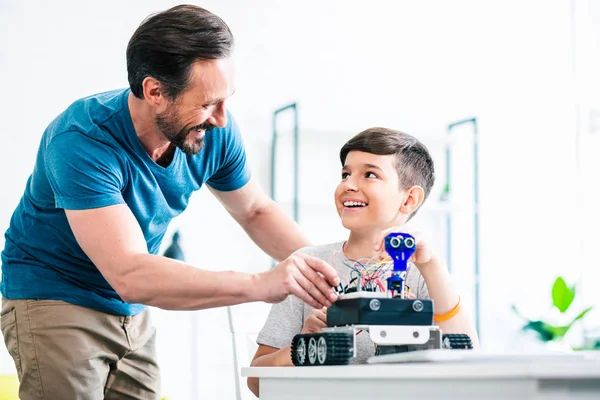 快乐英俊的男人帮助他的儿子 而测试新的机器人设备在家里 — 图库照片
