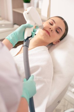 Lazer epilasyon için yüzüne özel cihazlar koyarak güzellik yaparken gözleri kapalı olan doğal makyaj ile Sakin bayan