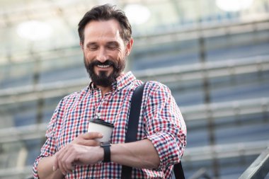 Zamanında kal. Joyful yakışıklı adam açık havada kahve içerken zaman kontrol