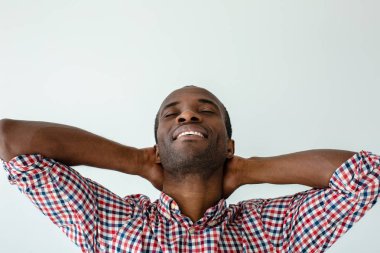 Tam dinlenme. Beyaz arka plan aleyhine dururken sevinçgözlerini kapatan olumlu afro Amerikan adam yakın