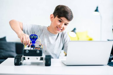 Masada oturan ve evde modern robot inşa pozitif bir küçük çocuk Bel kadar
