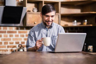 Güzel bir sabah. Neşeli adam haberleri online okurken kahve içme