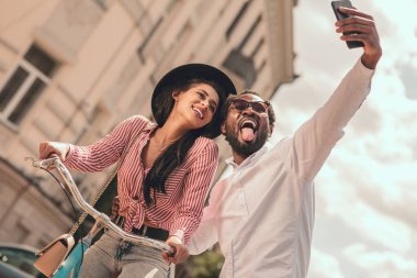 Komik adam selfie çekiyor ve bisiklette oturan gülümseyen kadın