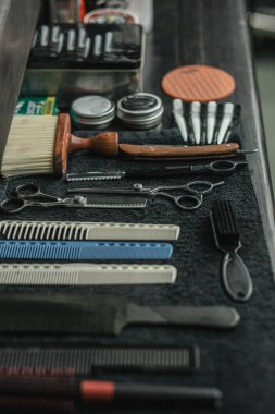 Tarak fırçaları yakın makası jilet ve tarak siyah havlu üzerine yerleştirilen