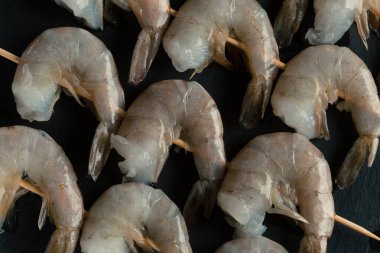 Siyah kayrak yüzeyinde üç şiş üzerine yerleştirilen ham kaplan karidesüst tespleri en iyi görüntü