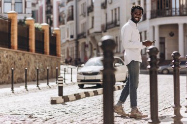 Neşeli genç adam akıllı telefon ile güneşli bir gün açık havada zevk. Web sitesi afişi