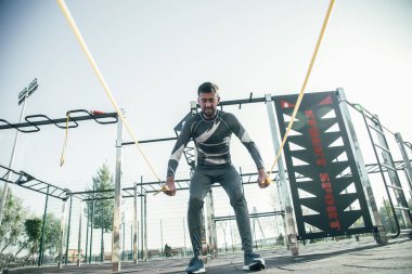 Kendine güvenen Mma boksör tek başına spor yerinde iken kaslarını eğitim ve lastik halatlar çekerek