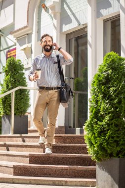 Mutlu sabahlar. Telefonda konuşurken gülümseyen pozitif yakışıklı adam