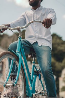 Güzel mavi bir bisiklete binen ve gülümseyen bir adamın kırpılmış fotoğrafı