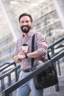 Güne iyi bir başlangıç. Neşeli yakışıklı adam açık havada yürürken kahve içme