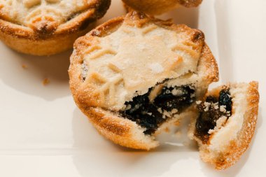 Beyaz kare tabakta şeker tozlu kıyma turta kapatın. Bir tabak köşesinde yatan yaban mersini reçeli ile pasta parçası