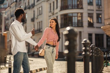 Sokakta onunla el ele tutuşurken erkek arkadaşına gülümseyen iyi görünümlü genç bayan