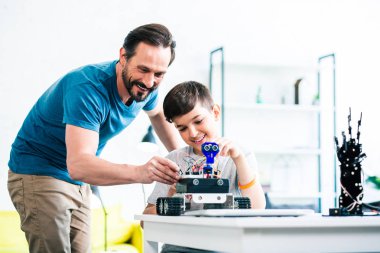 Birlikte robotik cihaz inşa ederken neşeli sevecen baba oğluna yardım