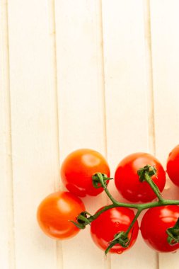 Çizgili ahşap yüzey üzerinde yatan ve taze görünümlü kırmızı kiraz domates dalı üst görünümü