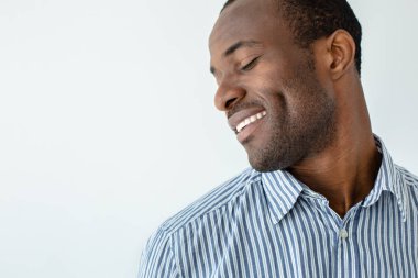 Gülümsemeye devam et. Beyaz arka plan aleyhine duran neşeli afro Amerikan adam yakın çekim