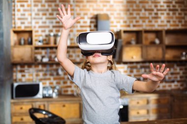 Yeni gerçeklik. Neşeli gülümseyen küçük kız Vr gözlük takarken evde istirahat