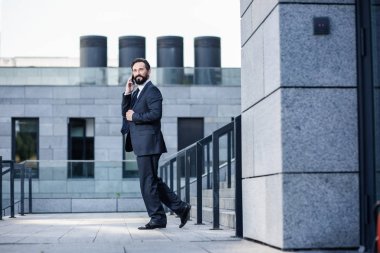 Modern yaşam tarzı. Neşeli kendinden emin işadamı gülümseyerek telefonda konuşurken