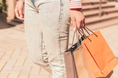 Üç kağıt torba taşıyan kadının elinin yakınçekim