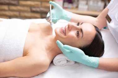 Oksijen spreyi tedavisi sırasında heyecan hisseden genç kadının yakın çekim ve dermatolog eldiven giyen ve özel bir araç tutarak