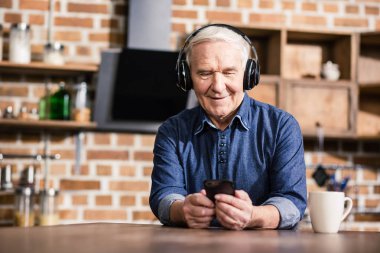 Neşeli zaman. Müzik dinlerken evde oturan mutlu güzel yaşlı adam