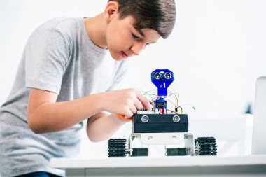Konsantre akıllı küçük çocuk mühendislik becerilerini geliştirirken bir robot inşa