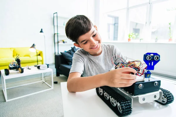 快乐聪明的男孩在做他的家庭作业时建造一个机器人装置 — 图库照片