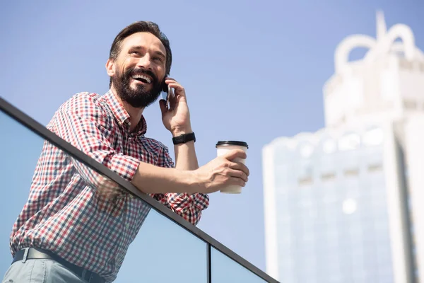 Glad to talk to you. Cheerful bearded man drinking coffee and having a conversation in the city