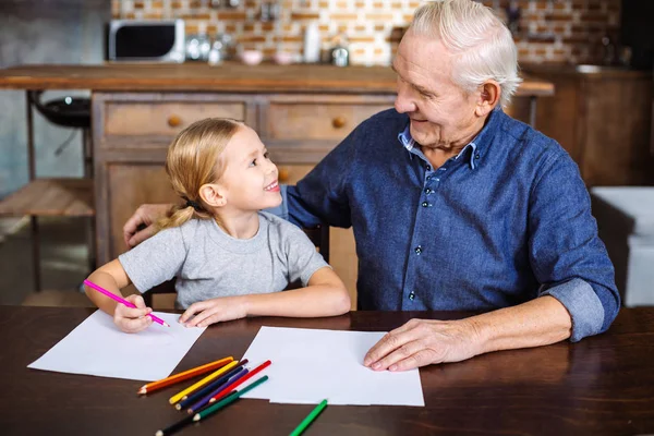 幸福的生活 快乐的小女孩坐在桌旁 他的祖父 而绘图 — 图库照片