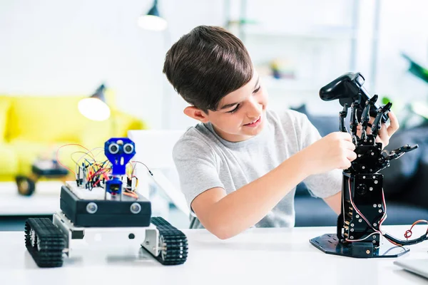 Keyifli gülümseyen öğrenci mühendislik okurken yeni robot cihazını test