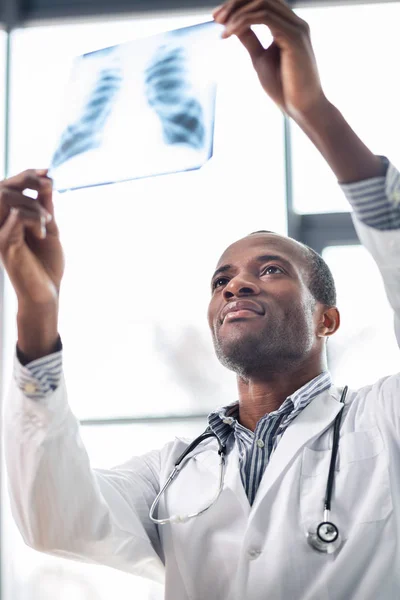 Social community. Competent medical worker pressing lips while staring at roentgen, raising arms