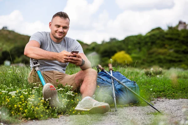 Jovem Encantado Com Deficiência Usando Seu Telefone Enquanto Descansa Grama — Fotografia de Stock