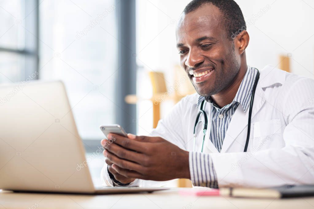 Enjoy your life. Cheerful brunette keeping smile on his face while doing his work with pleasure