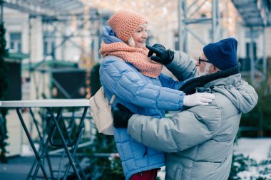 Kış giysileri yaşlı insanlar soğuk bir günde açık havada rahatlatıcı. Kocasının sol omzuna dokunan kadın