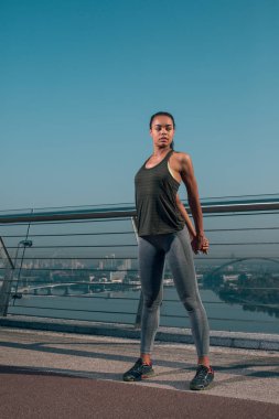 Sakin genç bayan ellerini arkadan koyarak ve köprüde ısınma