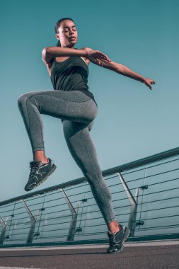 Barışçıl sporcu bir bacağını kaldırıyor ve ısınma egzersizinde vücudunu büküyor