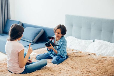 Kız kardeşiyle yatakta oturup popüler blogları için video kaydeden mikrofonlu pozitif çocuk.