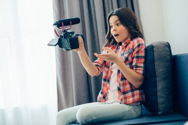 Evinde kanepede otururken blogu olan ve videolar çeken etkileyici bir genç kız.