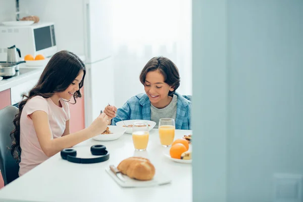 彼と一緒に朝食を食べながら いくつかの女の子は正の男の子とキッチンテーブルに座って笑顔 — ストック写真