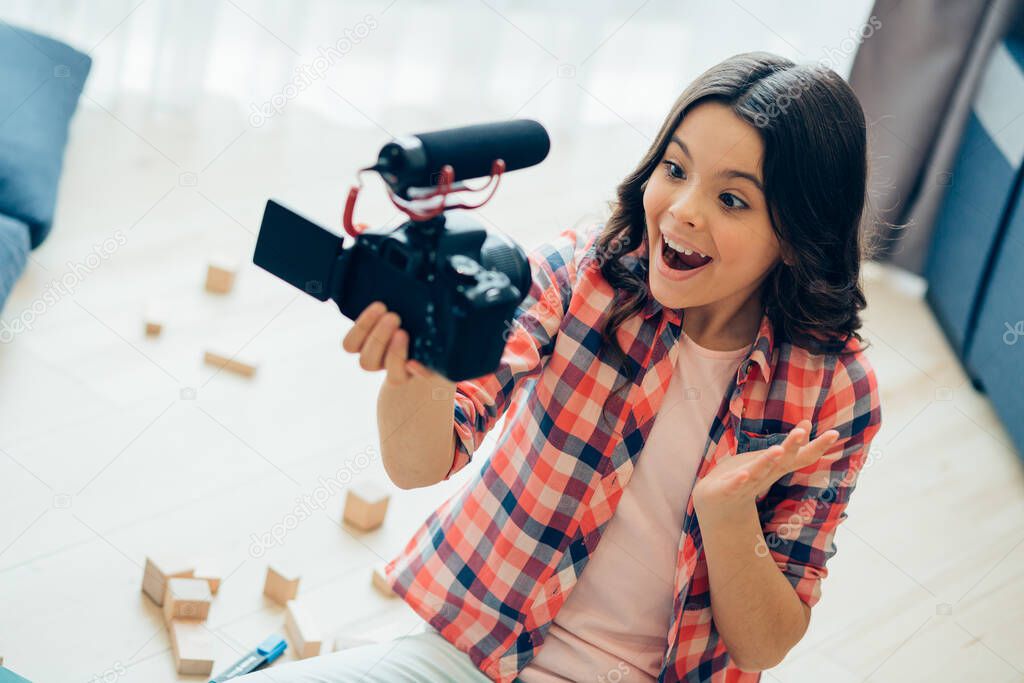 Cute happy girl gesturing and smiling while leading a video blog and recording herself on a camera