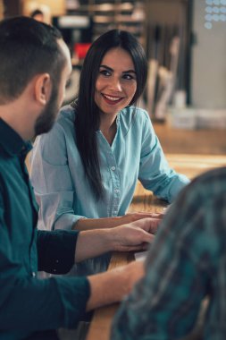 Masada arkadaşının yanında oturan neşeli genç kadın onu dinlerken gülümsüyor.